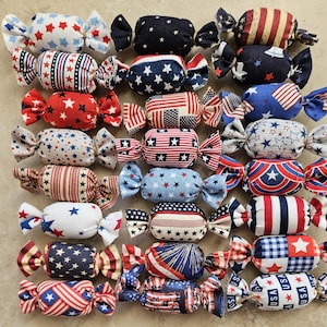 May include: A collection of 24 handmade fabric candy-shaped ornaments in red, white, and blue patriotic colors with various star and stripe patterns.