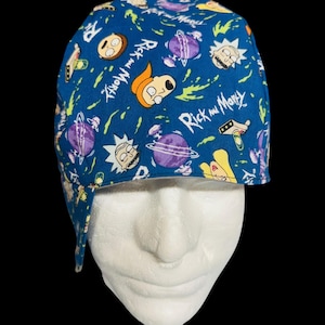 May include: A blue scrub cap featuring a repeating pattern of Rick and Morty characters, purple planets, and green portal splatters. The fabric displays the white Rick and Morty logo text scattered throughout the design on a dark blue background.