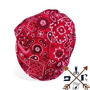 May include: Red bandana print welding cap. The cap features a classic paisley pattern in red, black, and white. The cap is designed to protect the head and hair from sparks and heat during welding.