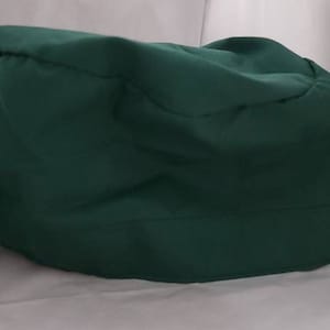 May include: A dark green surgical scrub cap with a tie string. The cap is made of a soft, breathable fabric.