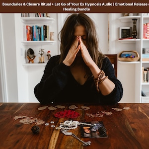 May include: A woman with hands clasped to her face sits at a wooden table. The table holds scattered decorative items, including a photo, beads, and small crystals. The image is part of a healing bundle.