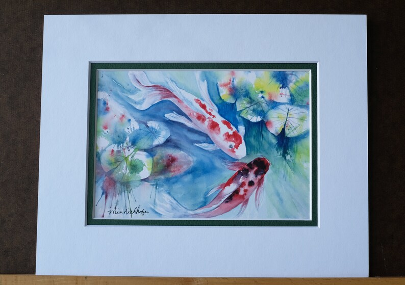 May include: Watercolor painting of three koi fish swimming in a pond with lily pads. The fish are red, white, and black with spots. The lily pads are green and yellow.