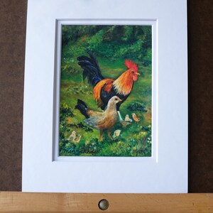 May include: A painting of a rooster and a hen with chicks. The rooster is red, orange, and black with a large comb. The hen is brown and white. The chicks are yellow and brown. The painting is set in a green grassy field.