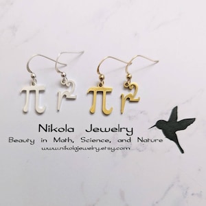 May include: A pair of silver and gold earrings featuring the mathematical symbol pi and the number 2, with a small hummingbird silhouette in the background. The earrings are on a white background. The text "Nikola Jewelry" is below the earrings, along with the tagline "Beauty in Math, Science, and Nature" and the website address "www.nikolajewelry.etsy.com".