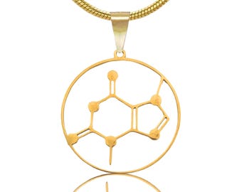 May include: A gold-colored necklace featuring a pendant with a molecular structure design. The pendant is a circular frame with the caffeine molecule's structure inside. The chain is a thin, gold-colored snake chain.