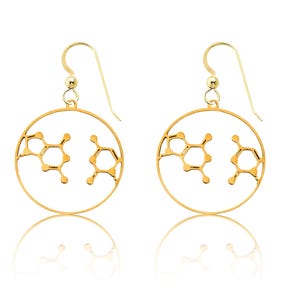 May include: A pair of gold-colored earrings featuring a molecular structure design. Each earring has a circular frame with the molecular structure cut out, and a hook for pierced ears. The earrings are displayed on a white surface.
