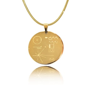 Op de afbeelding: Een gouden ketting met een ronde hanger met het ontwerp van de Voyager Golden Record. De hanger is gegraveerd met een gestileerde afbeelding van een plaat, een menselijke figuur, een diagram van het zonnestelsel en andere symbolen.