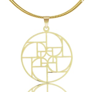 May include: A gold necklace with a geometric pendant featuring a circular design with intersecting lines and curves.