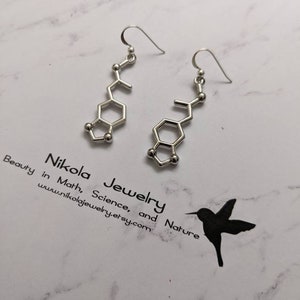 May include: Silver earrings shaped like a chemical molecule, with a hook closure. The earrings are on a white marble background with the text "Nikola Jewelry Beauty in Math, Science, and Nature www.nikolajewelry.etsy.com".