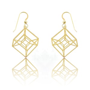 Op de afbeelding: Een paar gouden geometrische oorhangers met een kubusontwerp. De oorbellen zijn gemaakt van dun metaal en hebben een delicate, moderne uitstraling.
