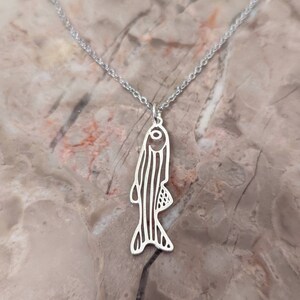 May include: A silver necklace featuring a delicate fish pendant. The fish is outlined and has a detailed design.