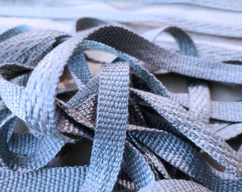 May include: A close-up of a pile of blue and gray ribbon. The ribbon is woven and has a subtle shimmer.