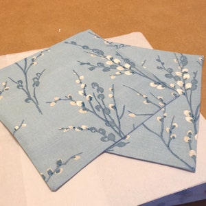 May include: Two light blue cushion covers with a white floral pattern. The fabric has a subtle linen texture.