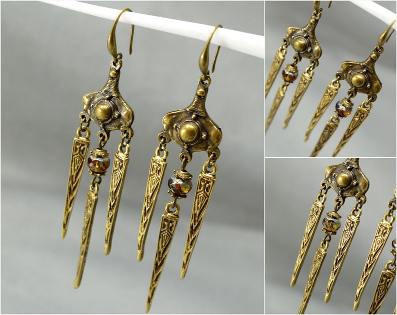 May include: A pair of gold-toned dangle earrings with three pointed teardrop-shaped charms and a small round bead on each earring.