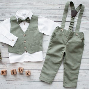 Può includere: Un gilet verde con papillon, una camicia bianca abbottonata, pantaloni verdi con bretelle e la parola "KIDZ" scritta con blocchi di legno.