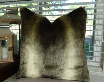 May include: A soft, plush pillow with a faux fur texture in shades of brown and white. The pillow has a gradient effect, transitioning from a darker brown to a lighter white.