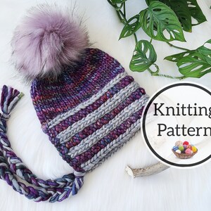 Puede incluir: Un gorro tejido a mano con un gran y esponjoso pompón lavanda. El gorro presenta bandas alternas de hilo morado y gris, con lazos trenzados. La imagen incluye el texto "Knitting Pattern" en un gráfico circular.