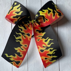 May include: A black and red bow with a yellow flame pattern. The bow is made of grosgrain ribbon.