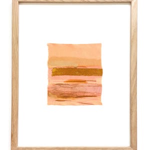 May include: A framed abstract art print with a pink and gold color scheme. The print is made of layered paper and has a textured surface.