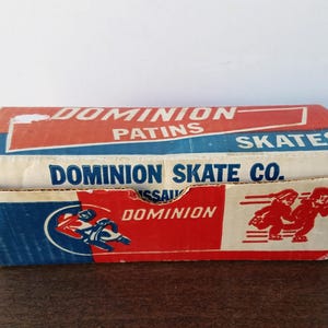 May include: Vintage Dominion Skates box. The box is primarily red, white, and blue, with the words "DOMINION PATINS SKATES" and "DOMINION SKATE CO." printed on it. The box features illustrations of skaters and a logo.