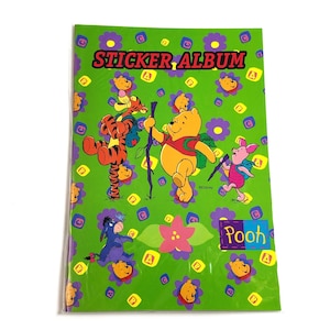May include: A green sticker album featuring Winnie the Pooh characters. The cover has the words "STICKER ALBUM" in red and yellow. The album is decorated with images of Pooh, Tigger, Piglet, and Eeyore, with the word "Pooh" in a blue box.