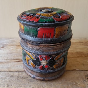 May include: A wooden box with a carved lid. The lid is painted with red, green, yellow, and black floral designs. The box is also painted with similar designs.