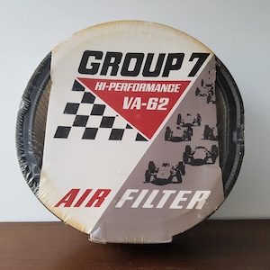 May include: A round, black and white air filter package with the text "GROUP 7 HI-PERFORMANCE VA-62 AIR FILTER" and a checkered flag design. The package features a graphic of race cars.
