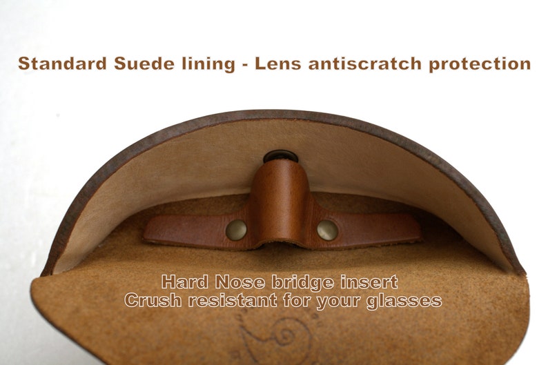 K&ouml;nnte beinhalten: Ein braunes Leder-Brillenetui mit einem Futter aus Wildleder. Das Etui hat einen harten Nasensteg-Einsatz, um Brillen vor dem Zerkratzen zu sch&uuml;tzen. Der Text "Standard Suede lining - Lens antiscratch protection" und "Hard Nose bridge insert Crush resistant for your glasses" ist auf dem Etui aufgedruckt.