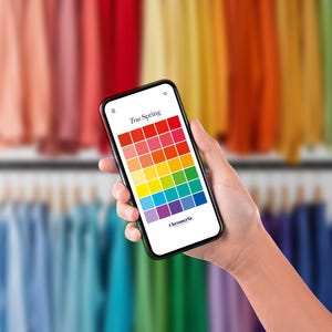 May include: A smartphone displaying a True Spring color palette on its screen, featuring a grid of various colored squares arranged in rows. The text True Spring and Chromeria are visible on the white screen interface against a blurred background.
