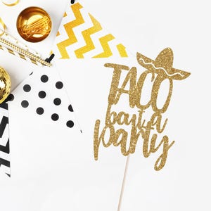 May include: Gold glitter cake topper with the text "Taco Bout a Party" and a sombrero.