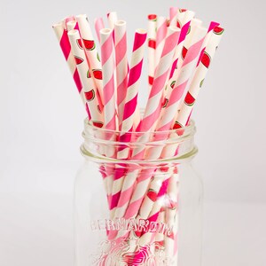 May include: A glass jar filled with pink and white striped paper straws with a watermelon print. The jar is labeled "Bernardin Mason".