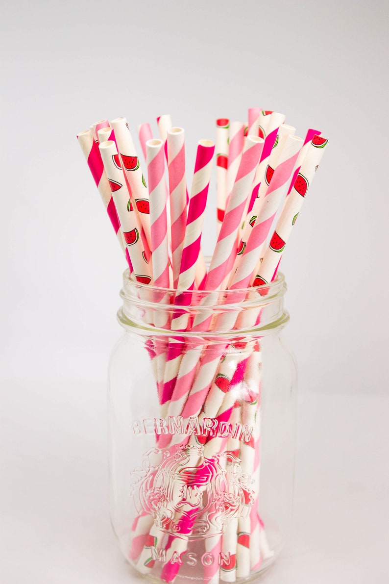 May include: A glass jar filled with pink and white striped paper straws with a watermelon print. The jar is labeled "Bernardin Mason".
