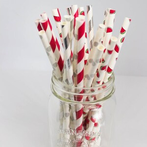 May include: A glass jar filled with red and white striped paper straws with watermelon print. The jar is labeled "Bernardin".