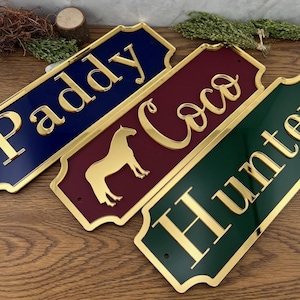 May include: Three rectangular nameplates in navy blue, burgundy, and hunter green with gold lettering. The navy plate reads "Paddy", the burgundy plate reads "Coco" with a horse silhouette, and the green plate reads "Hunter".