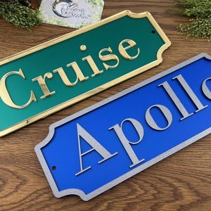 May include: Two decorative nameplates. One is teal with gold lettering that reads "Cruise". The other is blue with silver lettering that reads "Apollo". Both have a decorative border.