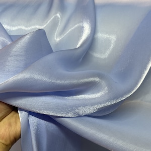 May include: Light blue satin fabric with a smooth, silky texture. The fabric is draped and folded, showcasing its sheen and drape.