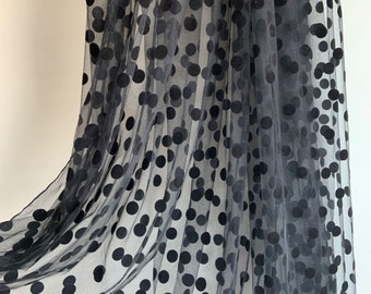 May include: Black sheer fabric with large black polka dots. The fabric is soft and has a delicate texture.