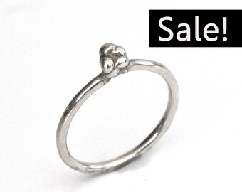 May include: A simple silver ring with a small, textured cluster of three spheres on the top.