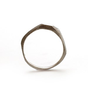Puede incluir: Un anillo de plata con un diseño geométrico texturizado.