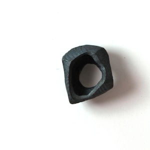 May include: A black, irregularly shaped ring with a large, open center. The ring is made of metal and has a rough, textured surface.