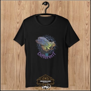 May include: Black t-shirt with a colorful graphic of a cicada with the text "Be Different" printed on it. The graphic is surrounded by a mandala design. The t-shirt has a small logo at the bottom that says "Dreaminglizard Graphics".