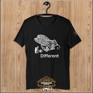 May include: Black t-shirt featuring a white graphic of a stylised cicada with the text "Be Different" underneath. The graphic is detailed and intricate. The t-shirt has a crew neck and short sleeves. The text "Dreaminglizard Graphics" is printed on the bottom of the shirt.
