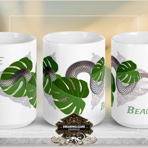 Op de afbeelding: Een witte keramische mok met een groene slang die om een groen monstera-blad gewikkeld is. De mok heeft de tekst "LIFE is BEAUTIFUL" erop gedrukt.