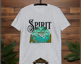 May include: A gray t-shirt with a green frog graphic and the text "Spirit Animal" in a stylized font. The text "dreaminglizard.com" is printed below the graphic. The t-shirt has a crew neck and short sleeves.