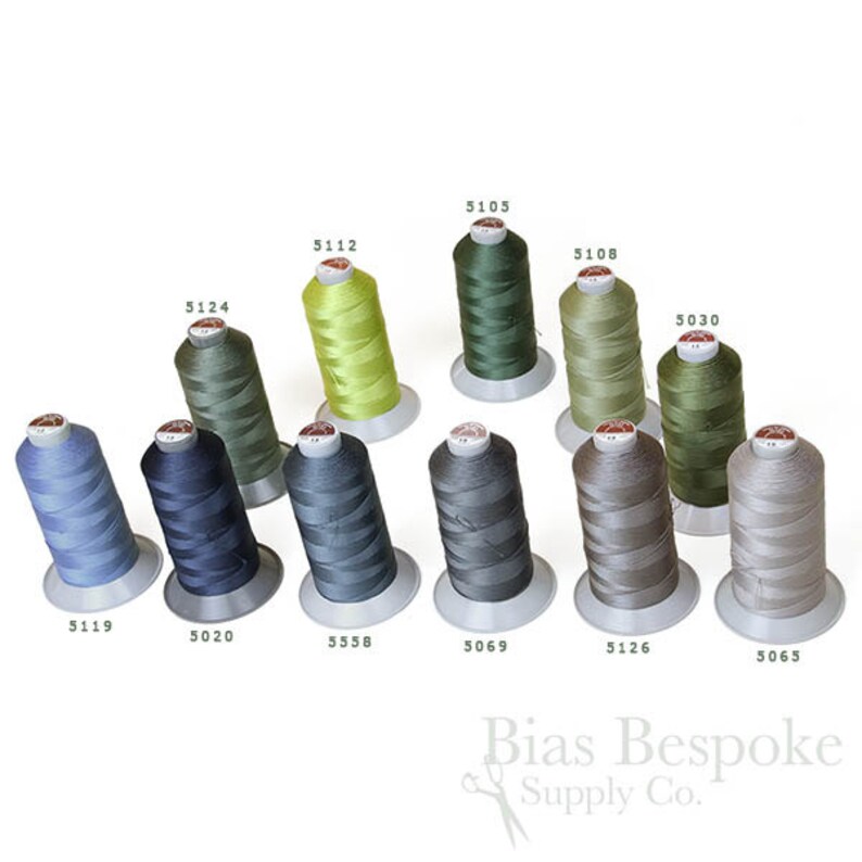 May include: An assortment of spools of thread in various shades of green, blue, and grey. The spools are labelled with numbers, including 5124, 5105, 5112, 5108, 5030, 5119, 5020, 5558, 5069, 5126, and 5065.