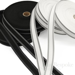 Puede incluir: Dos carretes de cinta rayada en blanco y negro. La cinta tiene 2,5 cm de ancho y un acabado satinado.