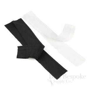 May include: Two strips of fabric, one black and one white, with a hook and loop fastener on one end of the black strip.  Brian Bespoke Supply Co.