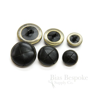 May include: Set of six black leather buttons with a gold trim. The buttons are different sizes and have a cross-stitch design.