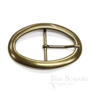 May include: A gold-toned oval belt buckle with a centre bar. The buckle is designed for a 1.5 inch wide belt.