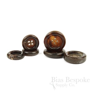 May include: A collection of five round, dark brown buttons with a marbled pattern and four holes in the center. The buttons vary in size and are arranged in a cluster. The text Bias Bespoke Supply Co. is visible in the bottom right corner.